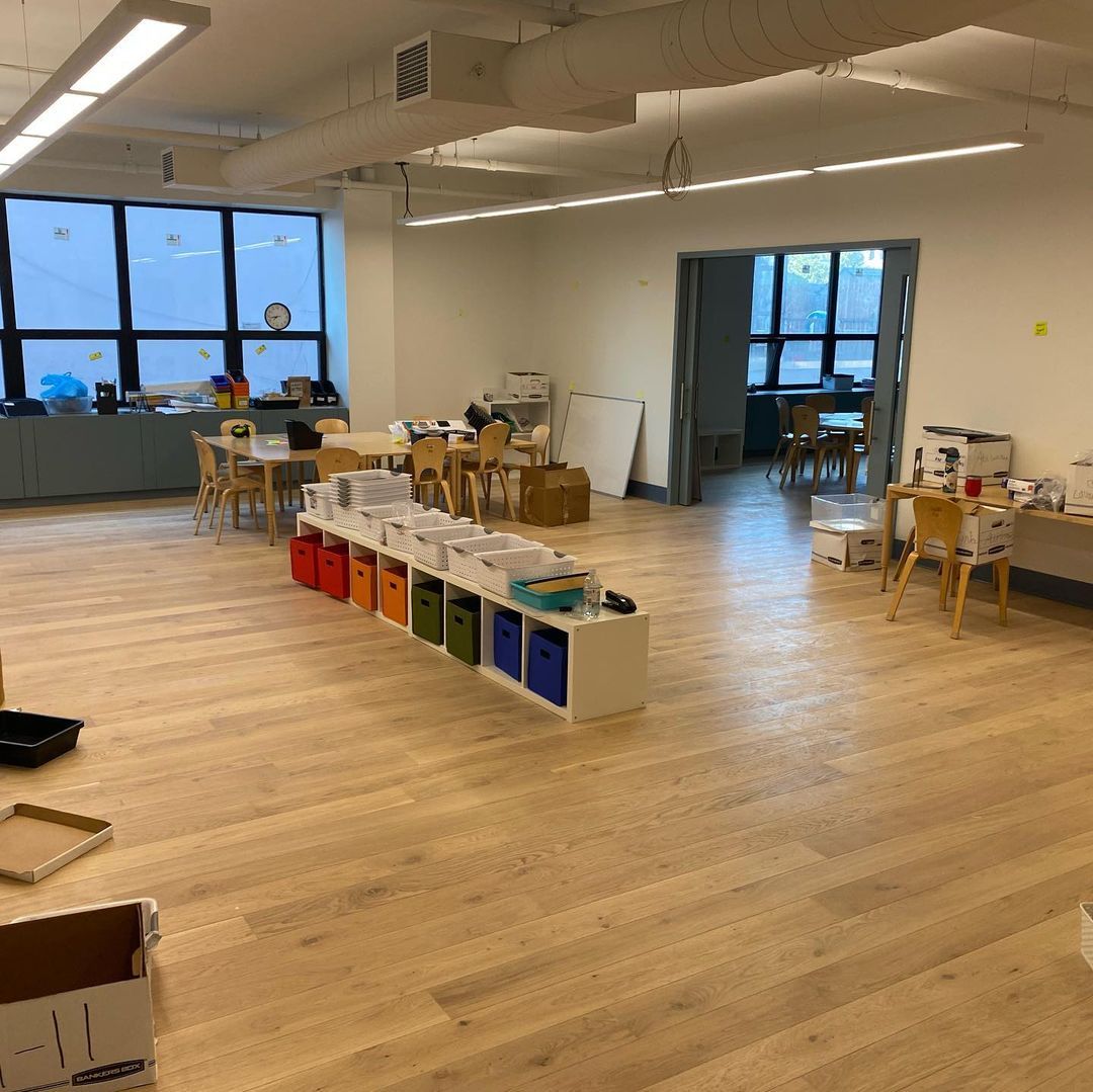 A large room with wooden floors and tables and chairs