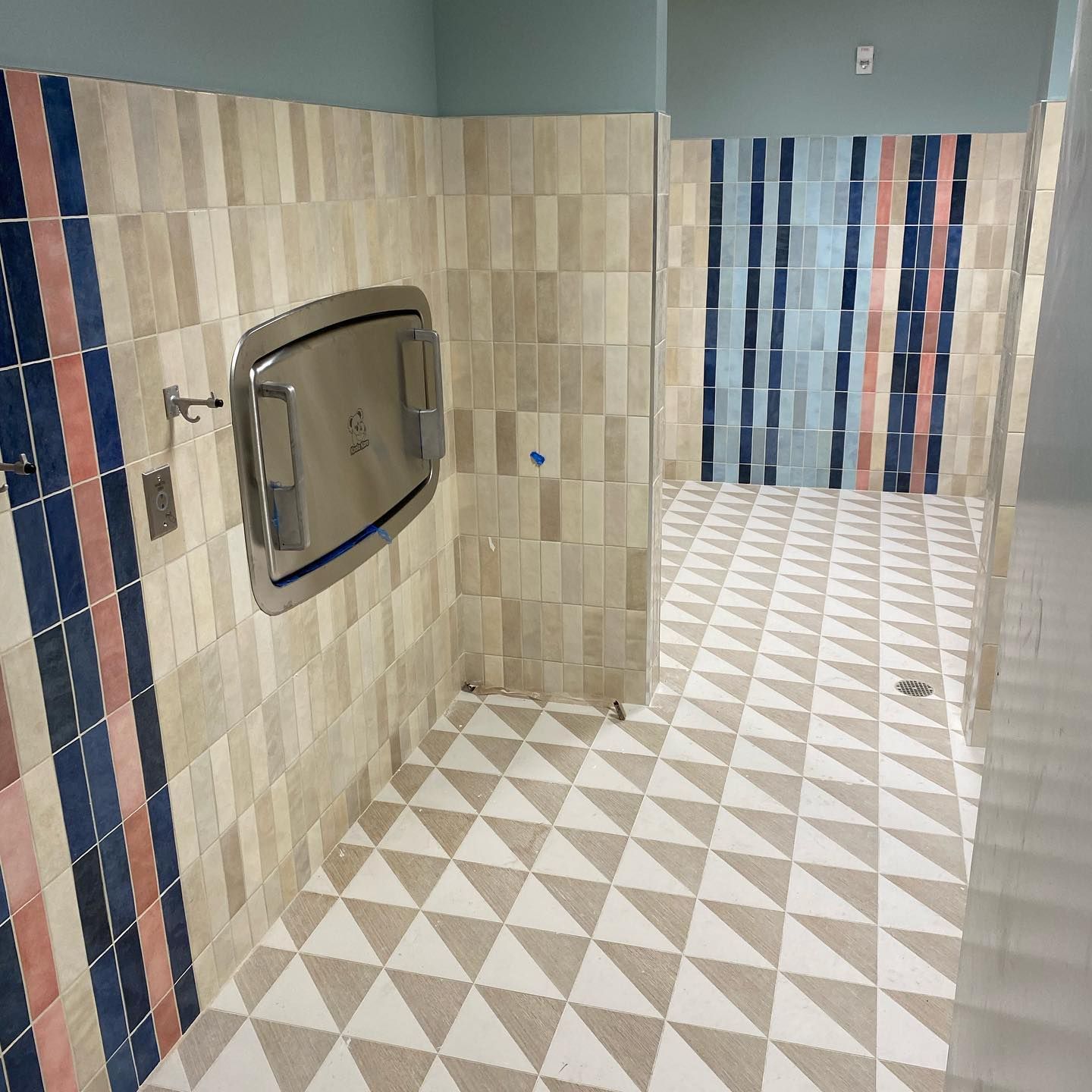 A bathroom with triangle tiles and a changing table