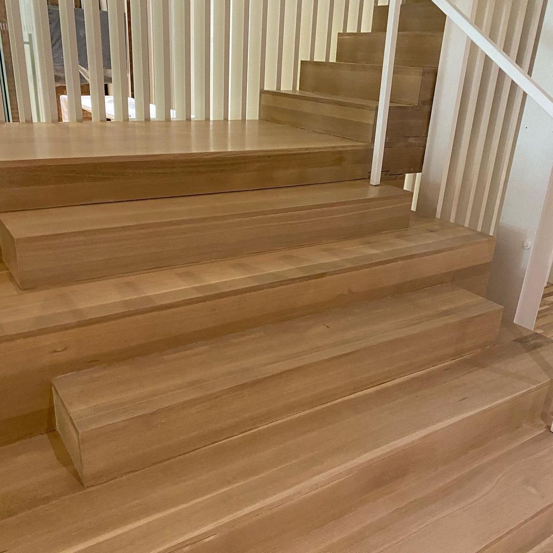 A close up of a wooden staircase with a white railing.