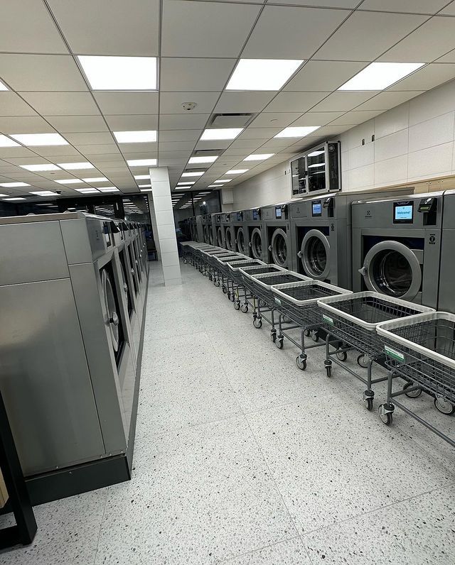 A laundromat filled with lots of washing machines and carts.