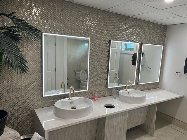 A bathroom with two sinks and three mirrors on the wall.