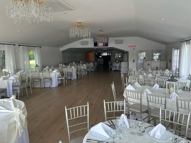 A large room with tables and chairs set up for a wedding reception