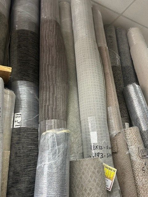 A bunch of rolls of carpet are stacked on top of each other in a room.