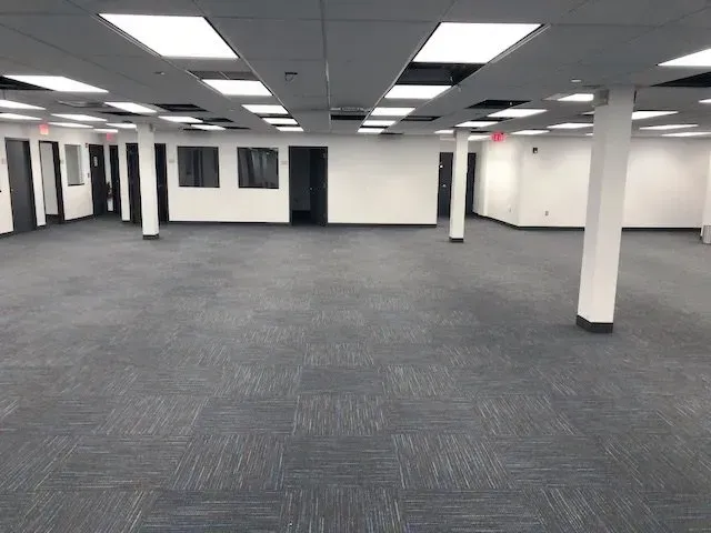 A large empty room with a gray carpet and white walls