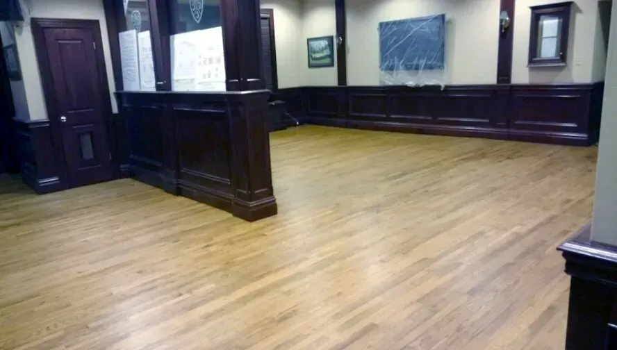 A room with a wooden floor and a chalkboard on the wall