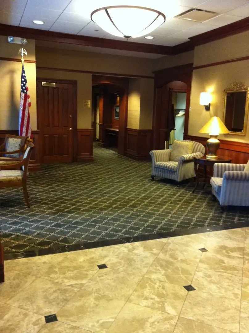 A lobby with chairs lamps and an american flag
