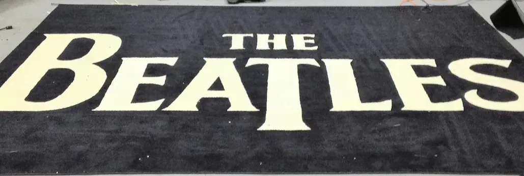 A large black rug with the beatles logo on it