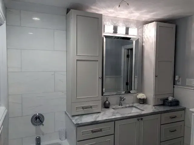 A bathroom with a sink , mirror and cabinets.