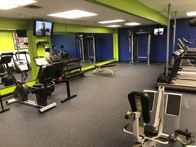 A gym with a lot of equipment and a large mirror