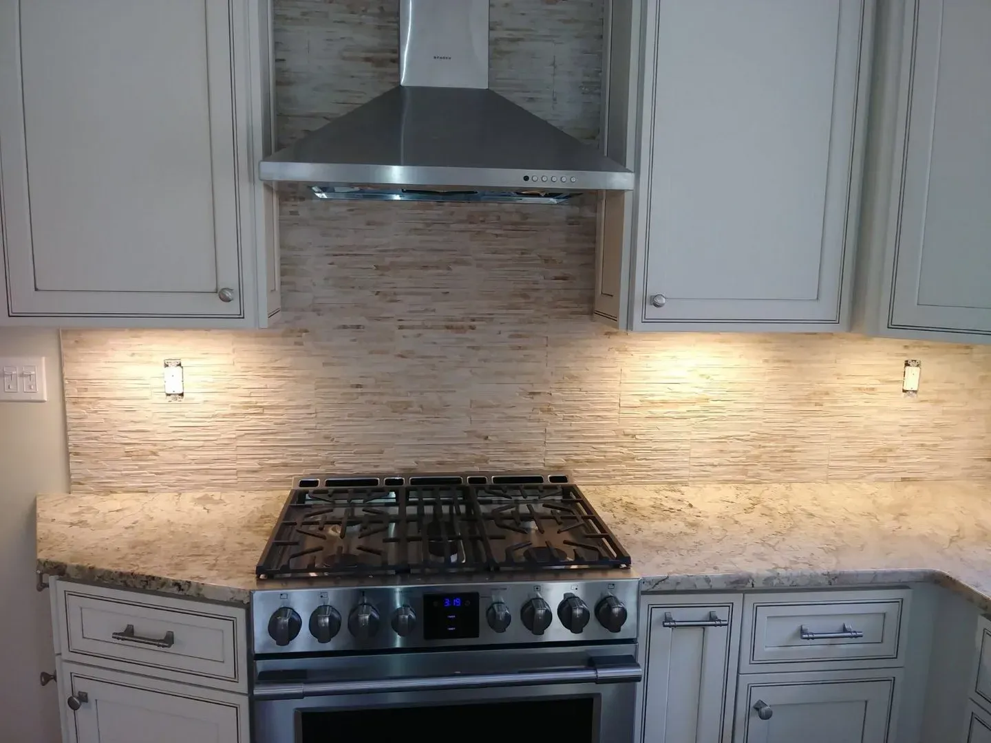 A kitchen with a stove top oven and a hood above it.