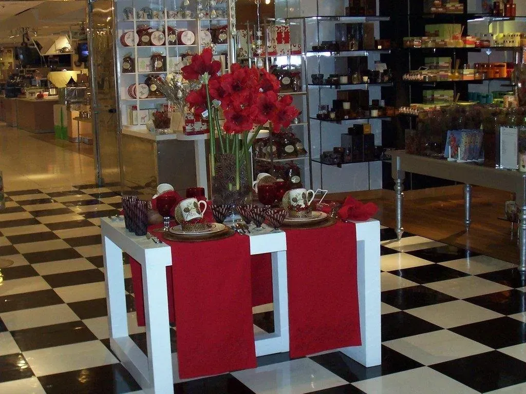 A black and white checkered floor with a table with red flowers on it