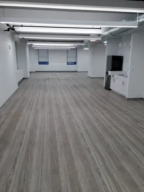 A large empty room with a wooden floor and white walls.