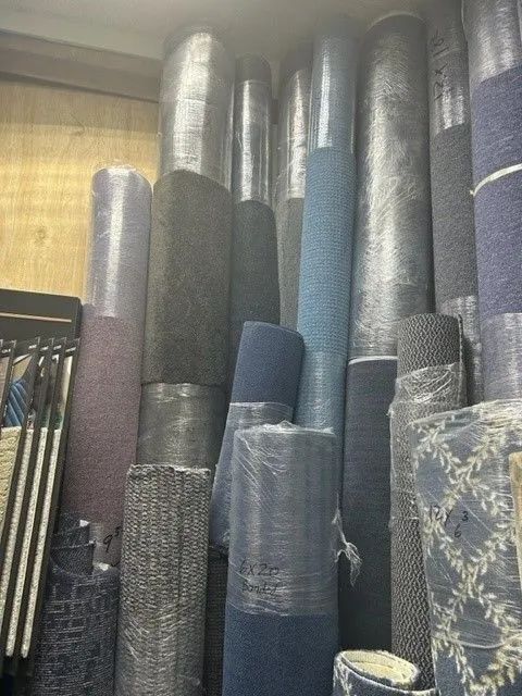 A bunch of rolls of carpet are stacked on top of each other in a room.