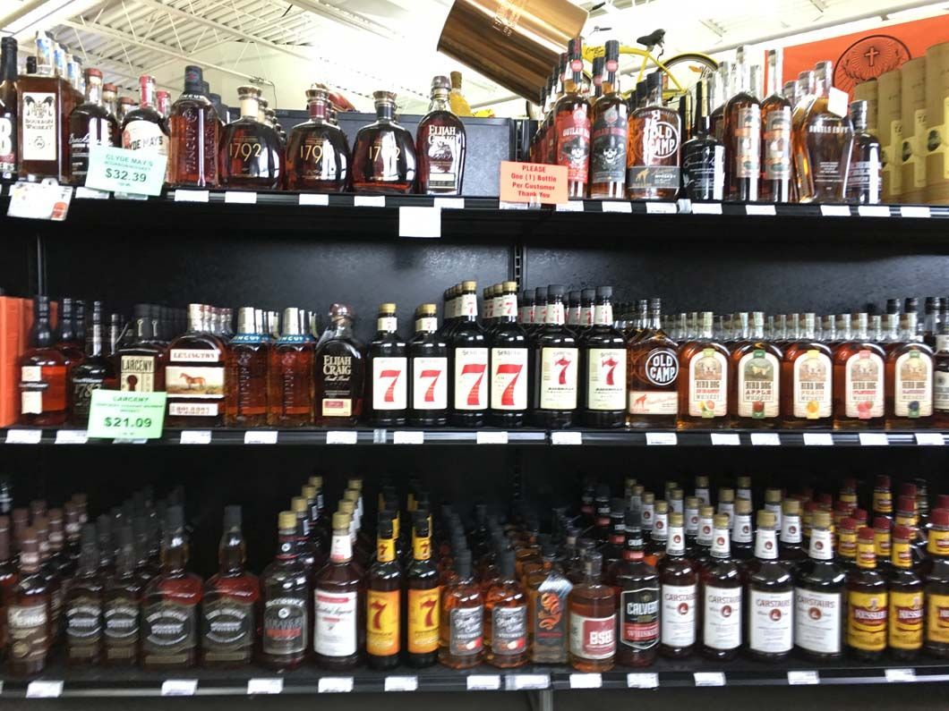 A liquor store shelf filled with lots of bottles of alcohol