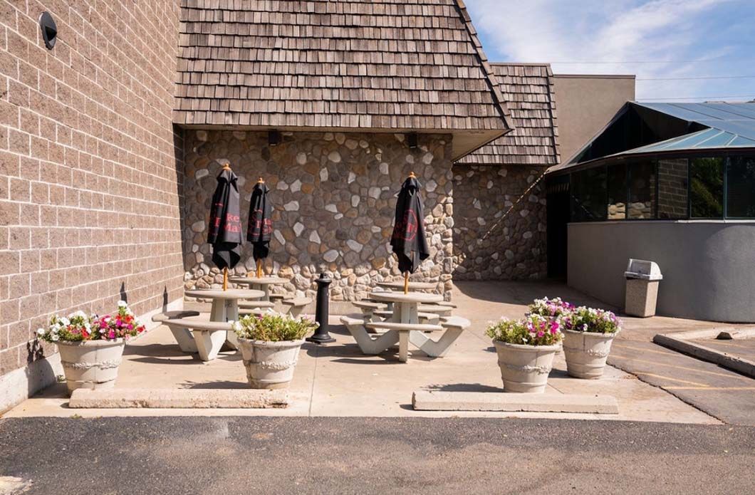 A patio with tables and umbrellas in front of a brick building.