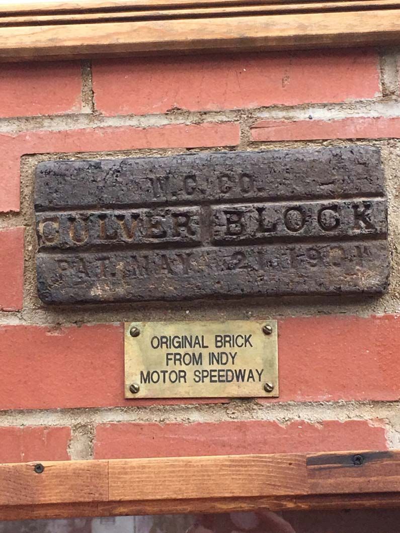 A brick wall with a plaque on it that says `` original brick from indy motor speedway ''.