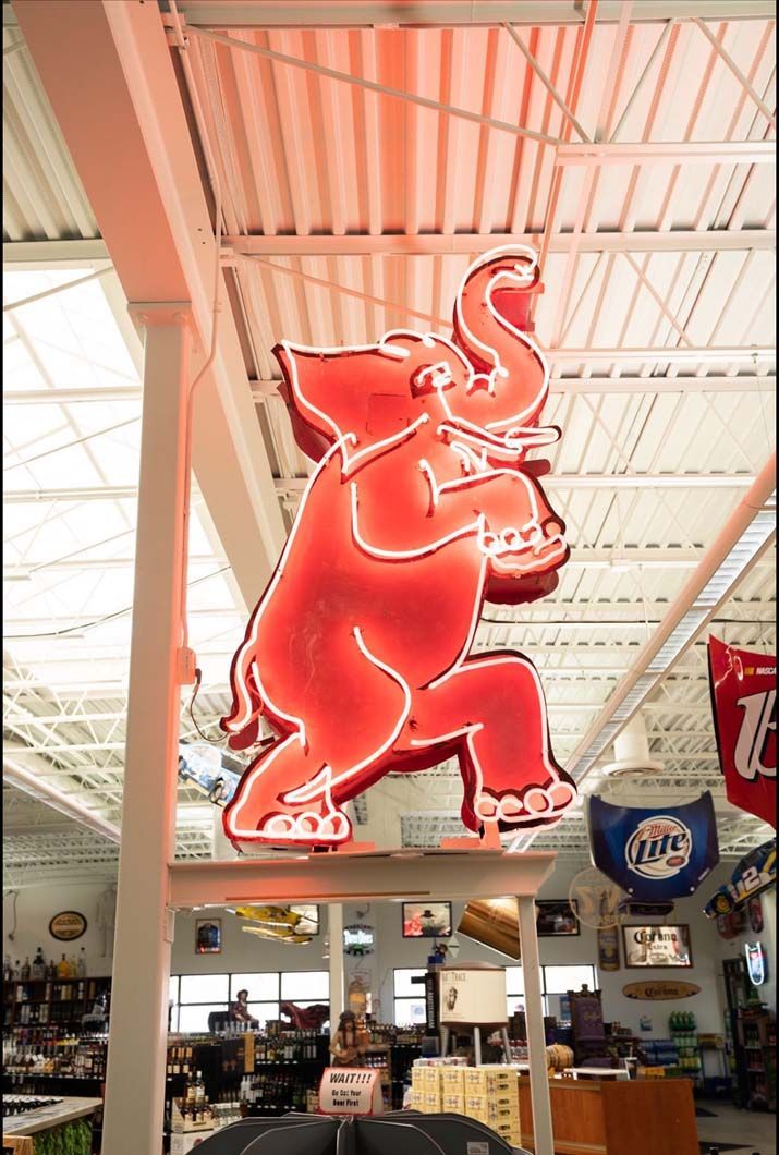 A neon sign of an elephant is hanging from the ceiling of a store