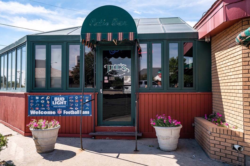 A restaurant with a green awning and a sign that says welcome