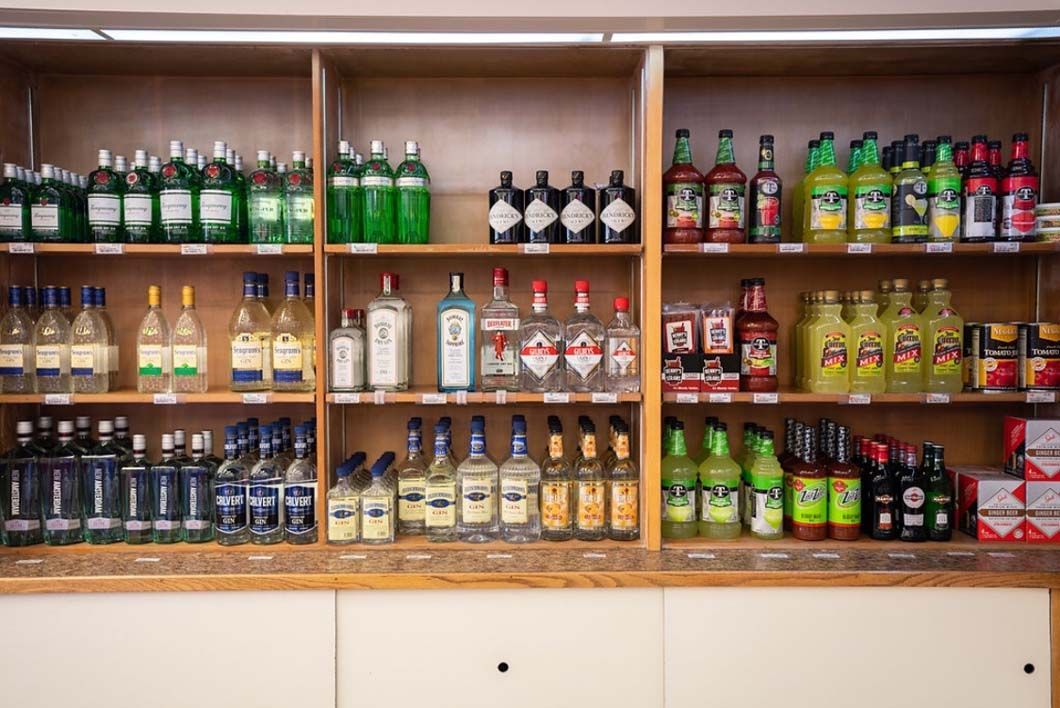 A shelf filled with lots of bottles of liquor and soda.