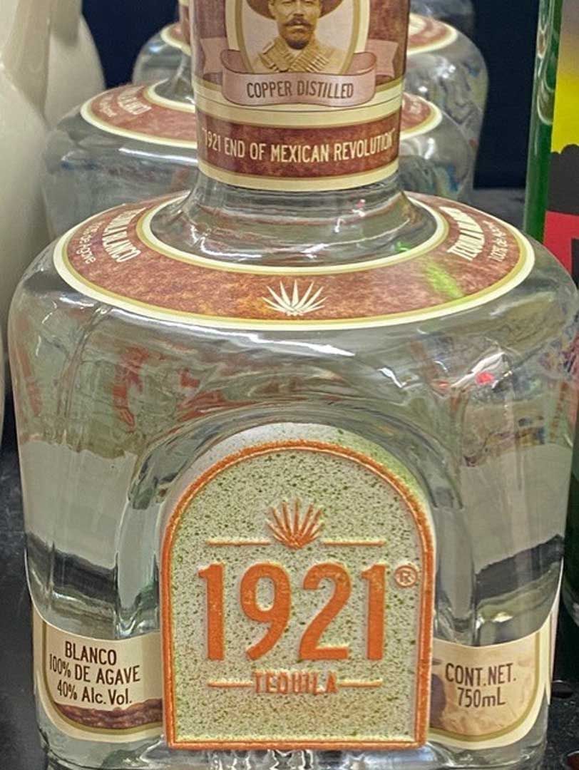 A bottle of 1921 tequila is sitting on a table.