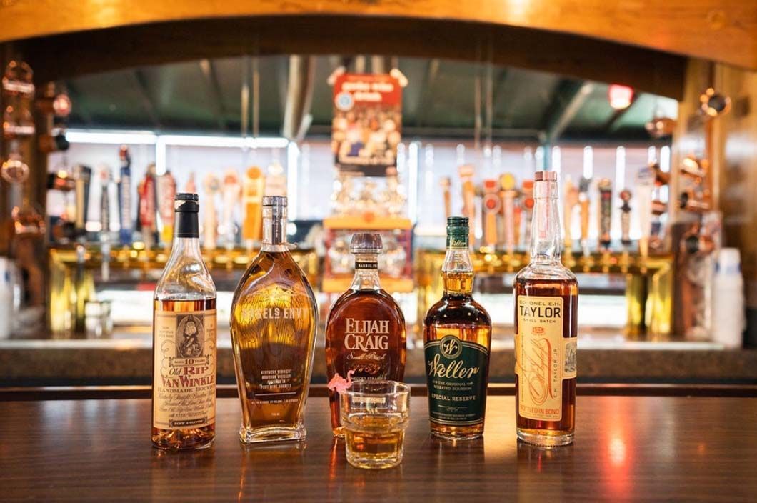 A group of bottles of whiskey are sitting on a bar.
