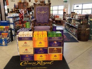 A crown royal chair is surrounded by boxes of liquor in a store.