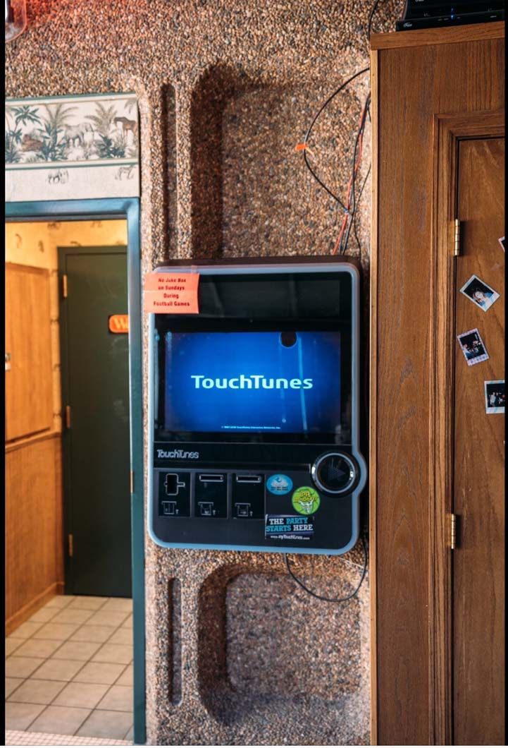 A touch tunes machine is hanging on a wall