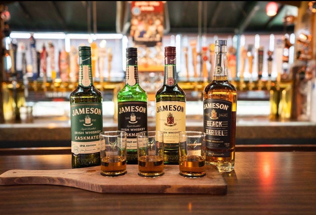 Four bottles of jameson whiskey are sitting on a wooden cutting board.