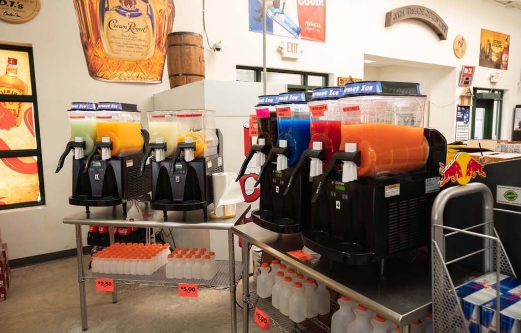 A row of slush machines are lined up on a table in a store.