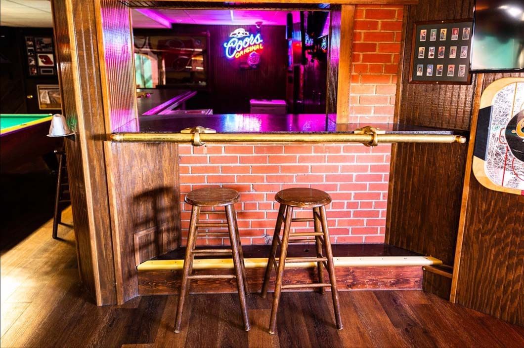 Two stools are sitting in front of a brick wall in a bar.