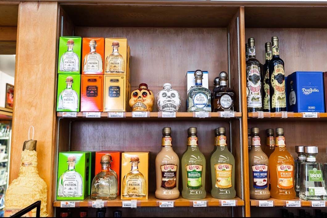 A shelf filled with bottles of liquor and boxes of liquor.