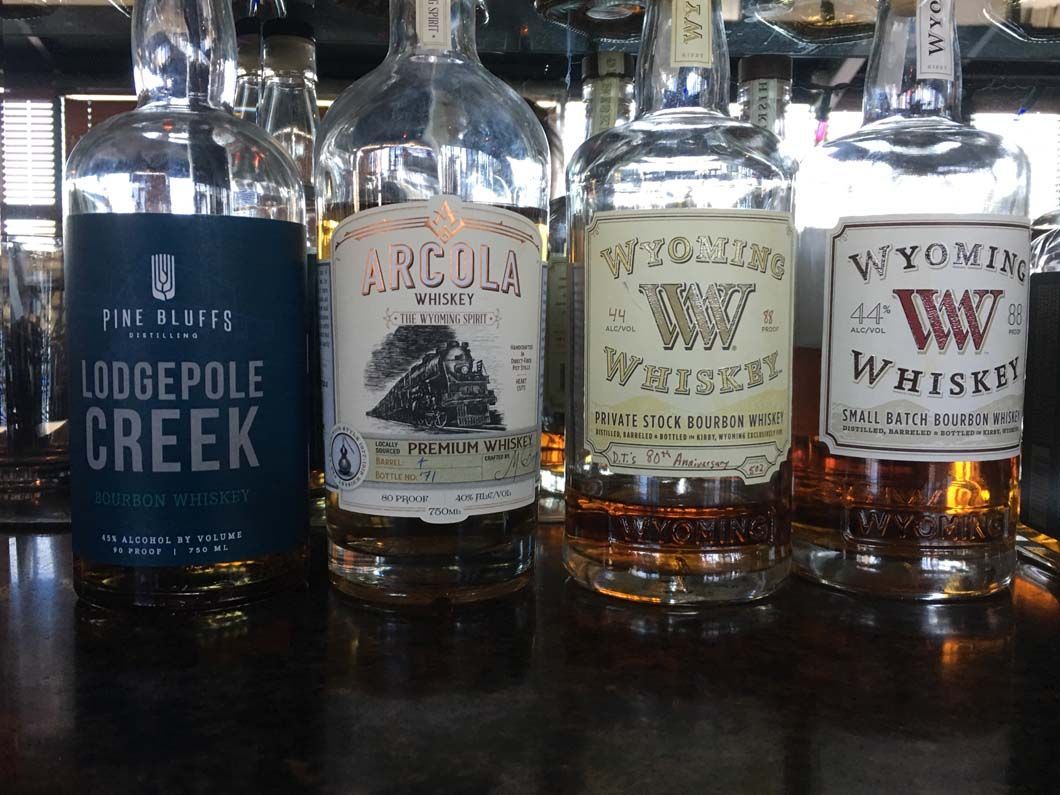 Four bottles of whiskey are lined up on a bar.