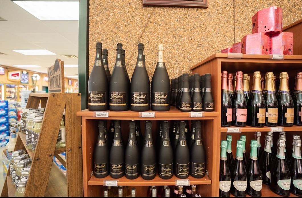 Bottles of wine are lined up on shelves in a store