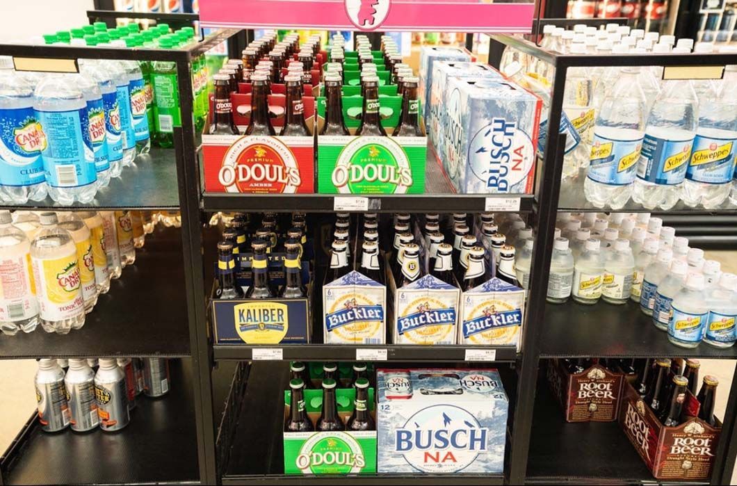 A grocery store shelf filled with bottles of beer and soda.