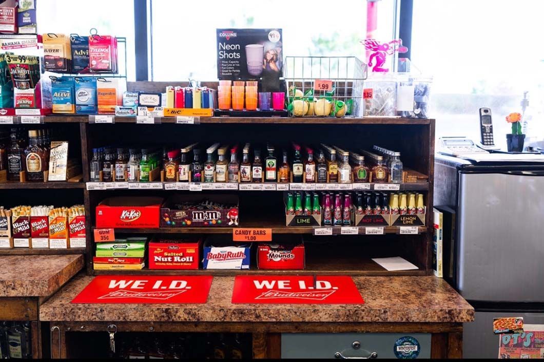 A store shelf filled with lots of bottles of alcohol and snacks.