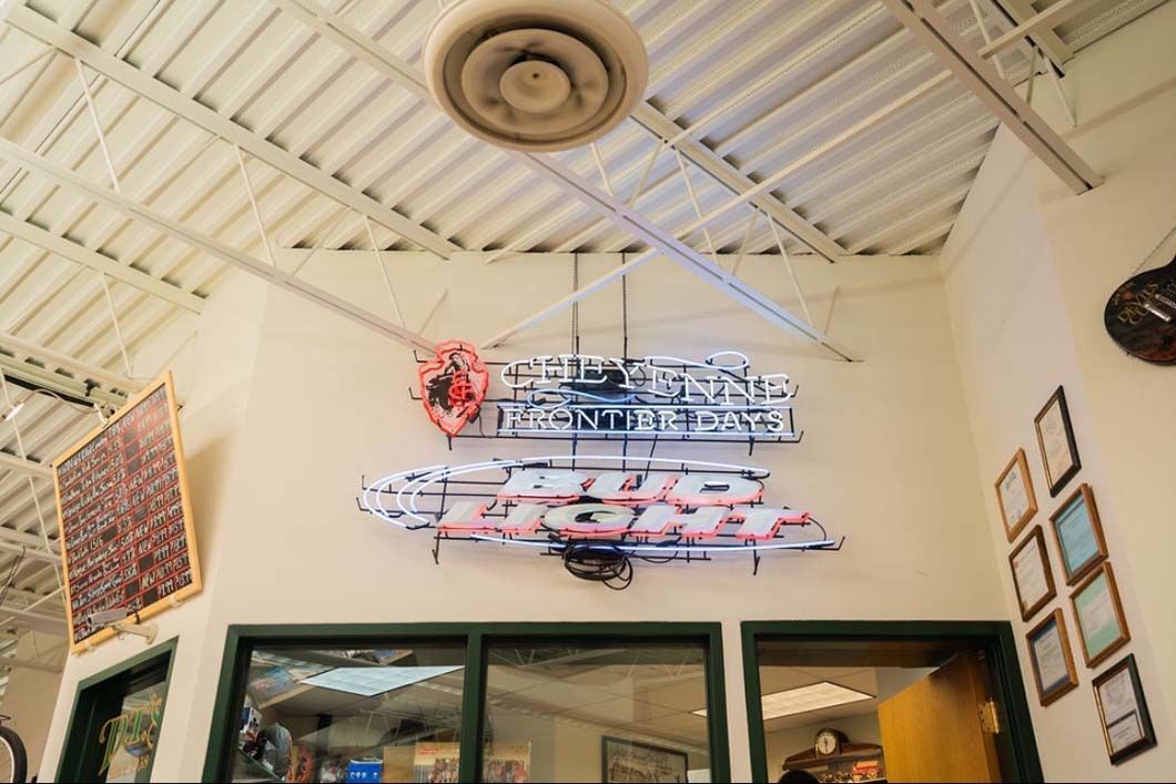 A neon sign is hanging from the ceiling of a building.