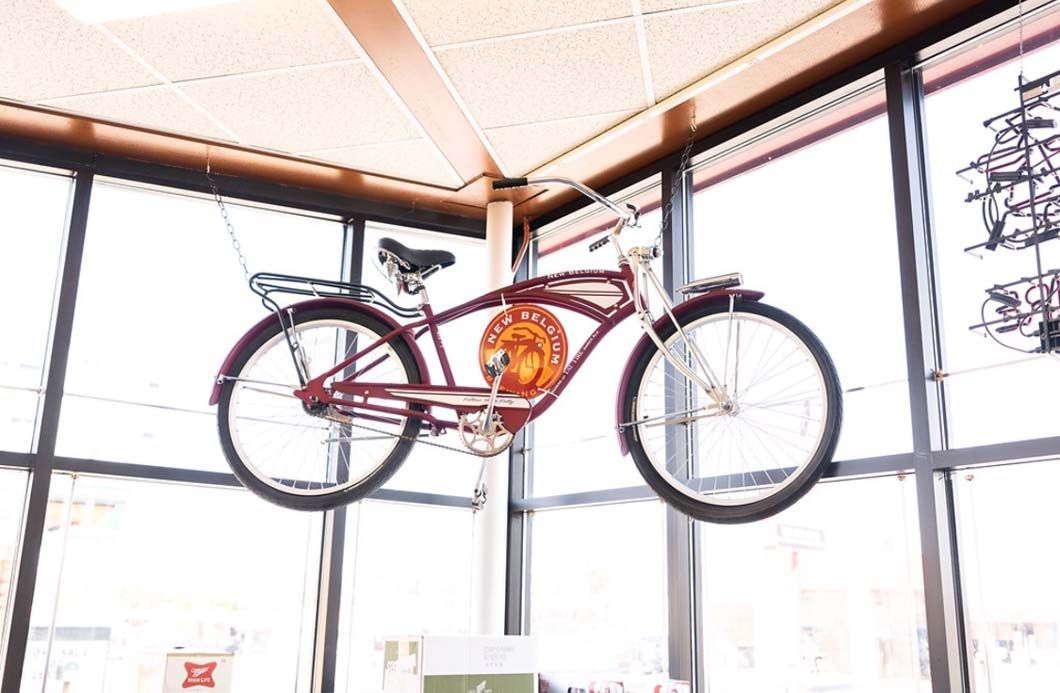 A red bicycle is hanging from the ceiling of a building.