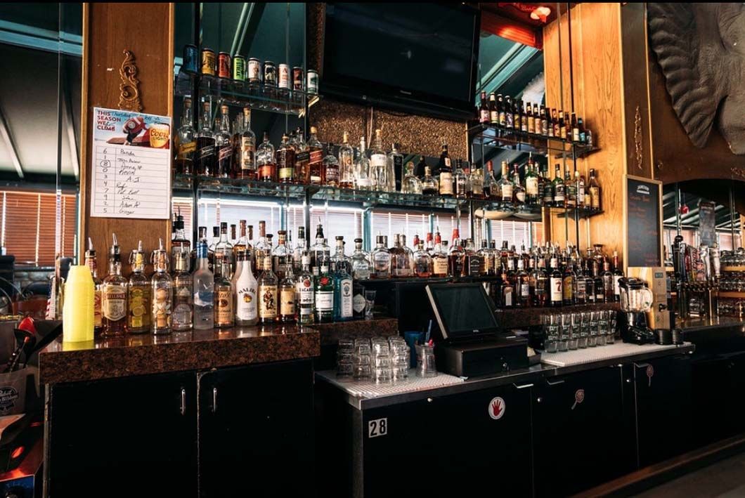 A bar filled with lots of bottles of liquor and a computer.