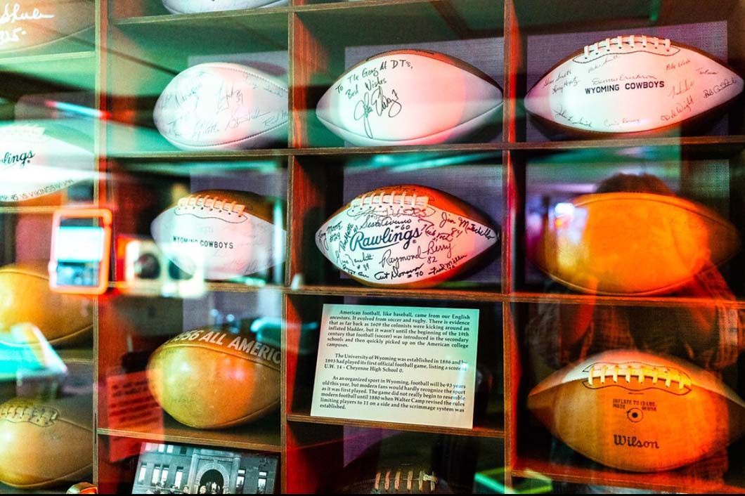 A display case filled with lots of different types of footballs.