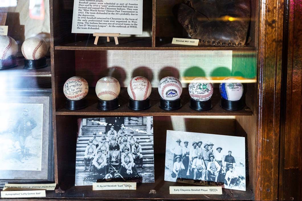 A display case filled with baseballs , pictures , and a glove.
