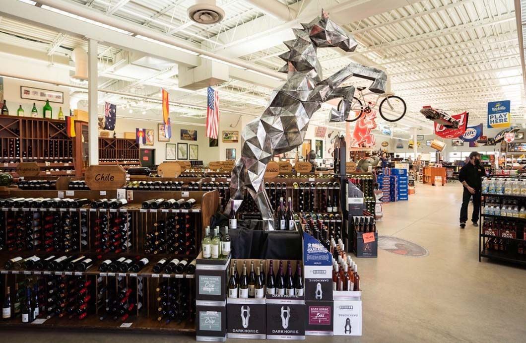 There is a statue of a horse in the middle of a wine store.