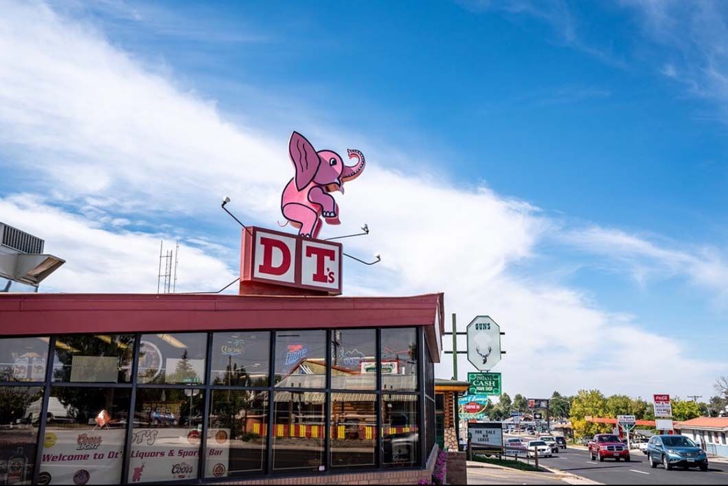 A pink elephant is sitting on top of a red building.