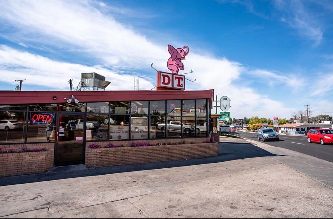 A restaurant with a pink pig on top of it.