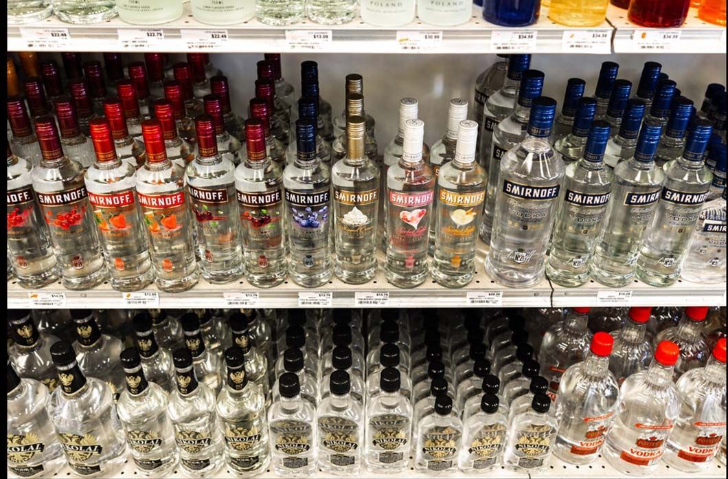 A shelf filled with bottles of vodka in a store.
