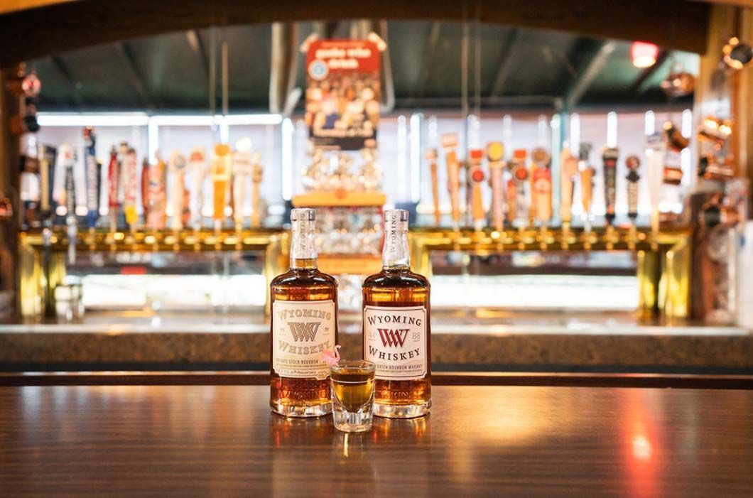 Two bottles of whiskey are sitting on a bar counter.