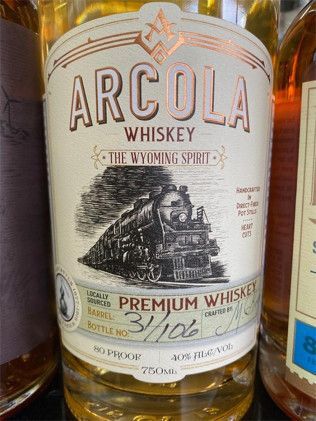 A bottle of arcola whiskey with a train on the label.