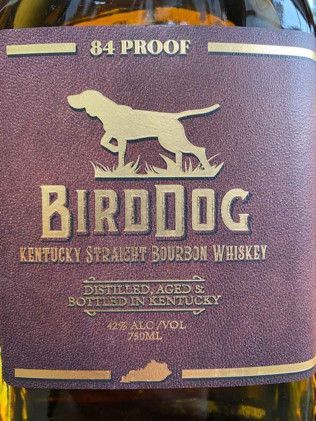 A bottle of birddog kentucky straight bourbon whiskey with a dog on the label.