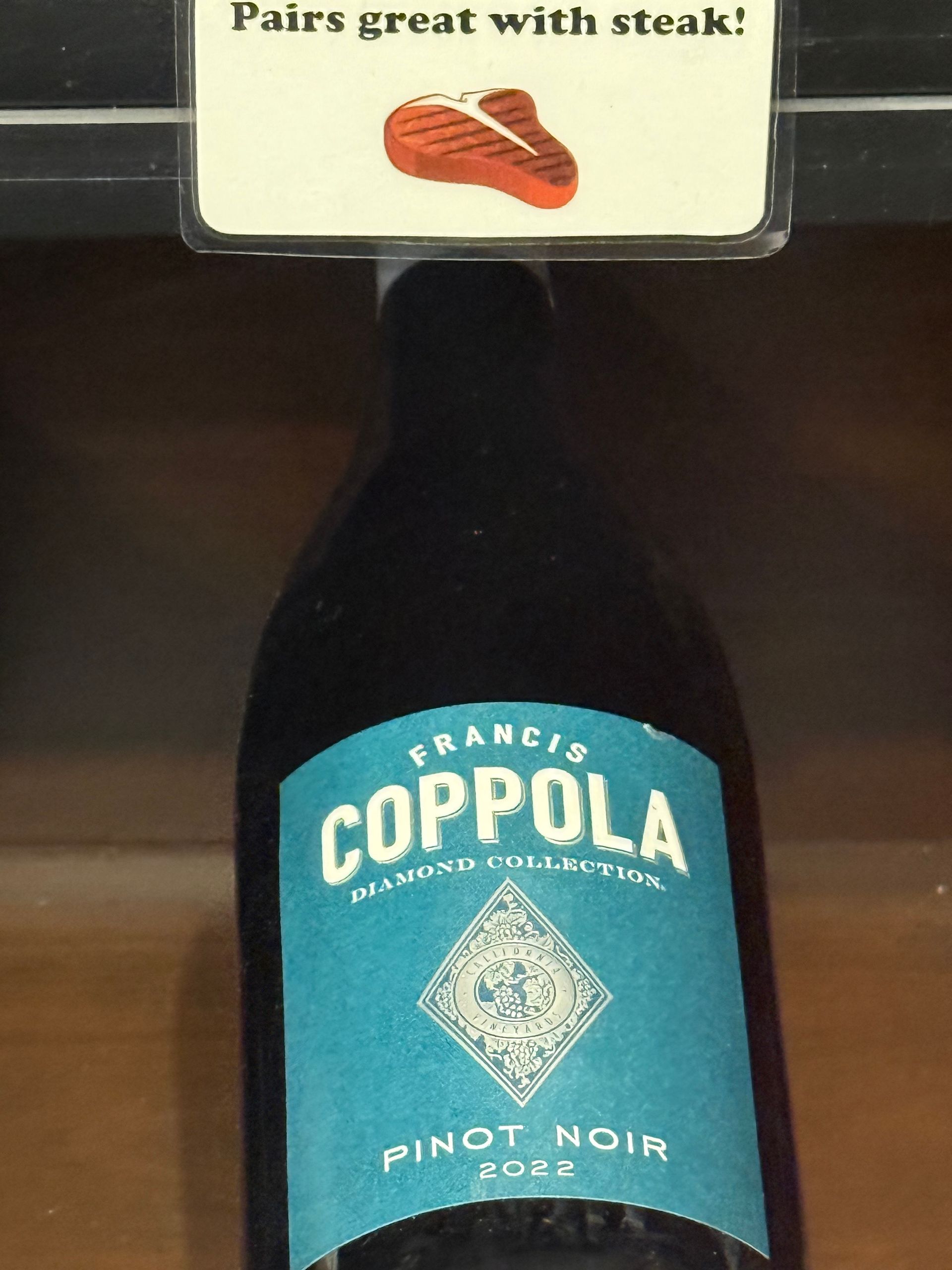 Francis Coppola Pinot Noir wine bottle with a blue label and a sign that reads