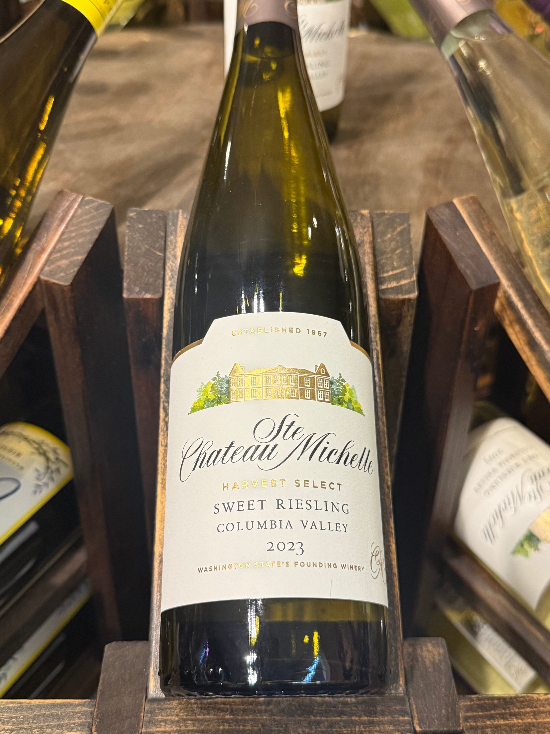Bottle of Chateau Ste. Michelle wine in a wooden rack; label visible.
