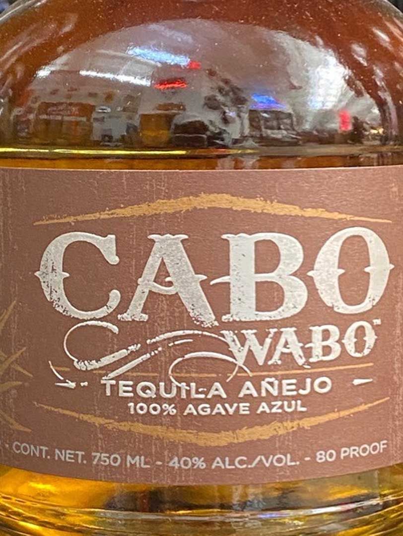 A bottle of cabo wabo tequila añejo 100 % agave azul is sitting on a table.